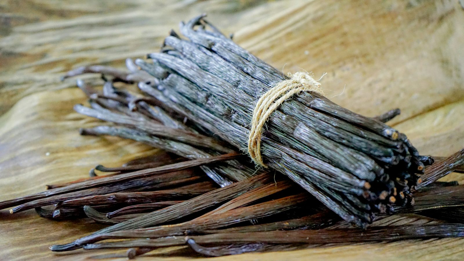 A bundle of cured vanilla beans tied with twine on a board